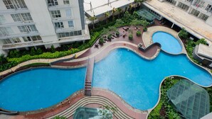 A rooftop pool with a curved design, surrounded by greenery and modern buildings.
