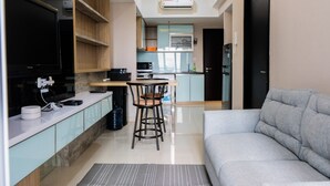 A modern living room with a grey sofa, a dining area with a table and chairs, and a kitchen with a microwave and cabinets.
