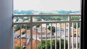 A view through a window with white bars, displaying a densely packed urban area with various buildings and rooftops.