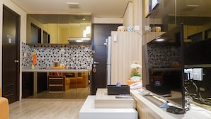 Una cocina moderna con salpicadero de azulejos, horno empotrado y refrigerador. Hay una encimera con un lavamanos y un microondas. Un televisor está montado en la pared sobre la encimera.