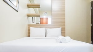 Una cama bien hecha con sábanas y almohadas blancas, un cabecero de madera y un pequeño adorno en la pared.