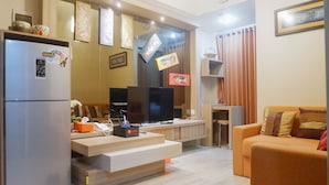 Una sala de estar moderna con un televisor de pantalla plana, un sofá, una mesa de centro y un refrigerador.