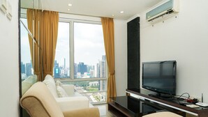Ein modernes Wohnzimmer mit großem Fenster, einem Flachbildfernseher, einer Couch und einem Sessel.