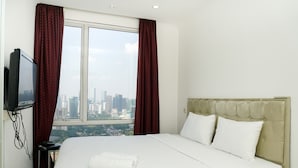 Ein Hotelzimmer mit einem großen Bett, einem an der Wand montierten Fernseher und Blick auf die Stadt durch das Fenster.