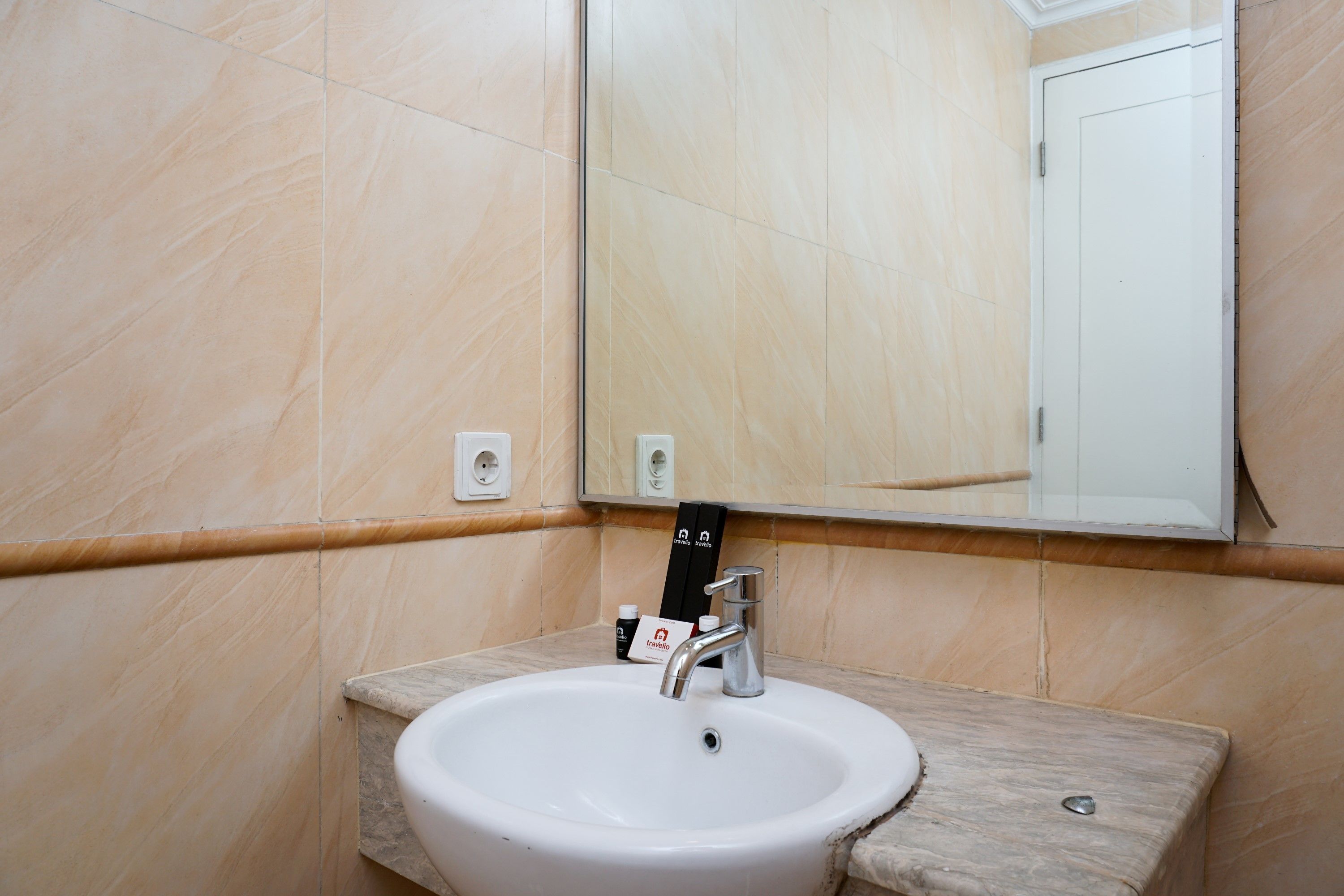A bathroom with a white sink, a mirror, and a marble wall.