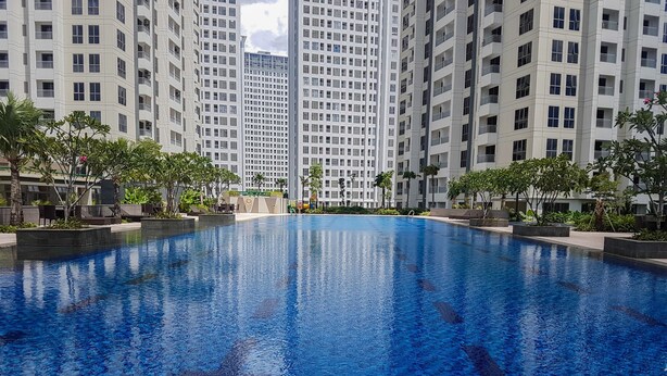 A swimming pool surrounded by high-rise buildings, with a clear sky above. - Minimalist 2BR Apartment at M-Town Residence (Gading Serpong)