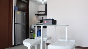 Una cucina compatta con frigorifero, piano cottura a gas e un piccolo tavolo con due sgabelli.