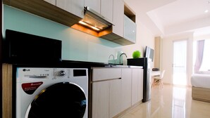 A modern kitchen with a washing machine, a microwave, and a built-in oven.