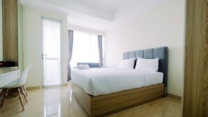 A modern bedroom with a large bed, a desk, and a chair.