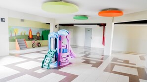 A spacious lobby with a colorful play area, a mural, and a patterned floor.