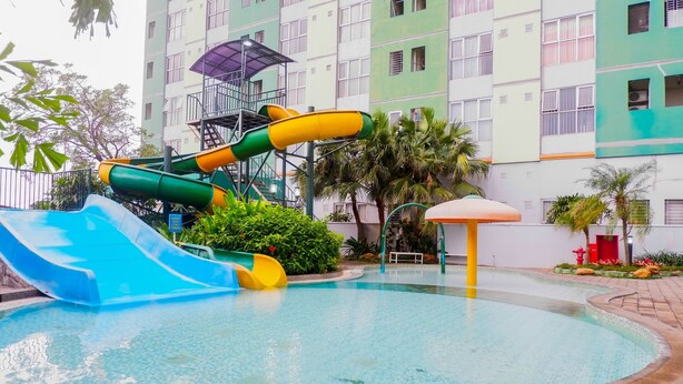 A swimming pool with a water slide and a sunshade.