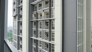 A multi-story residential building with balconies, large windows, and a view of a cityscape. - Strategic 1BR Apartment at Ciputra International (Jakarta)