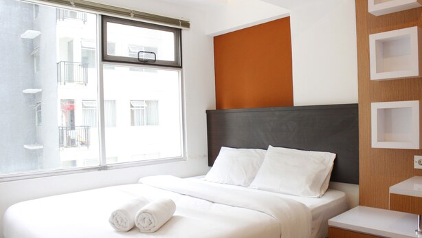 A hotel room with a bed, a window, a bedside table, and a built-in shelf. - Strategic 1BR Apartment with Sofa Bed at The Jarrdin Cihampelas (Bandung)