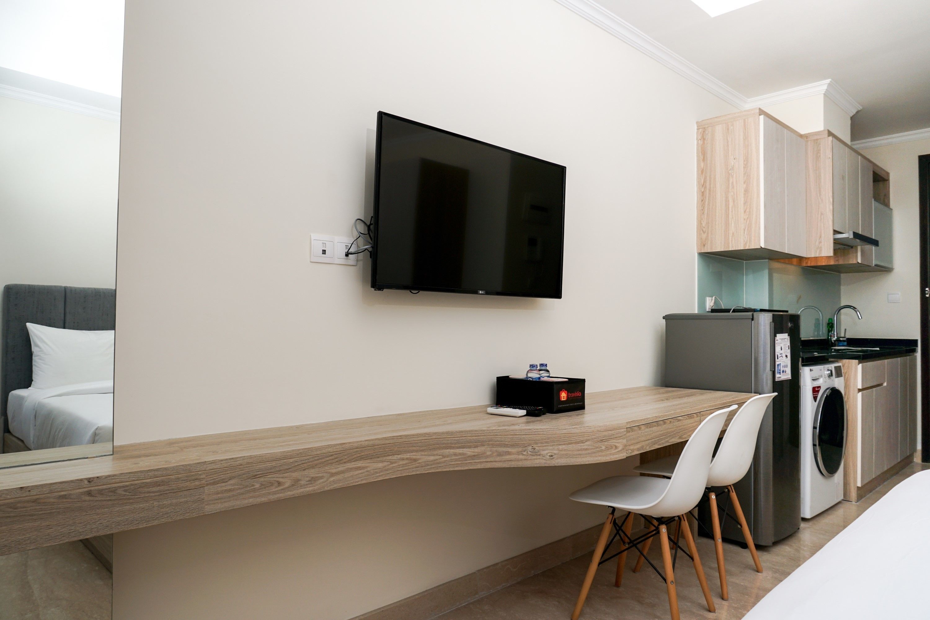 A modern kitchen with a built-in washing machine, a flat-screen TV mounted on the wall, and a wooden countertop.