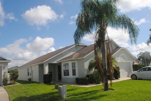 Set amidst a lush lawn, this charming home features a single-story design with a sloping roof and a welcoming entrance.