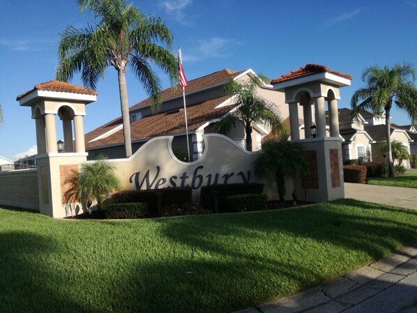 Experience the charm of Westbury, a Mediterranean-style residence with stucco walls and arched windows, set amidst lush lawns and palm trees.