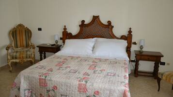 A bedroom with a large bed, a wooden headboard, a chair, and two bedside tables.