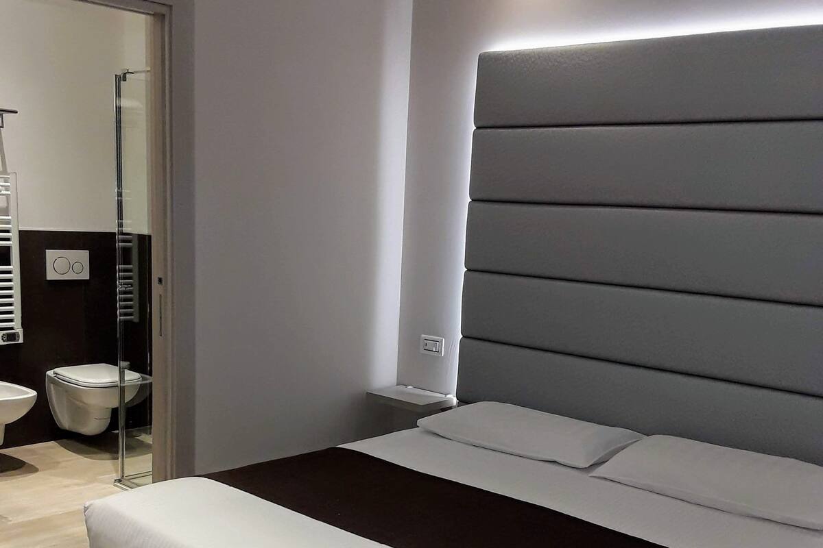 Ein modernes Schlafzimmer mit einem großen Bett, einem Nachttisch und einer Wandleuchte.