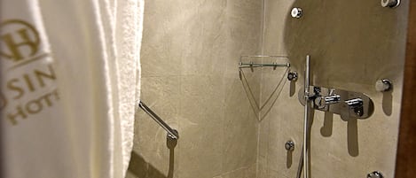 Un bagno d'hotel con doccia, asciugamano e scarico.
