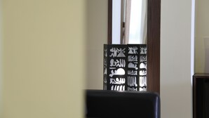 A room with a window, a black chair, and a decorative panel with Arabic calligraphy.
