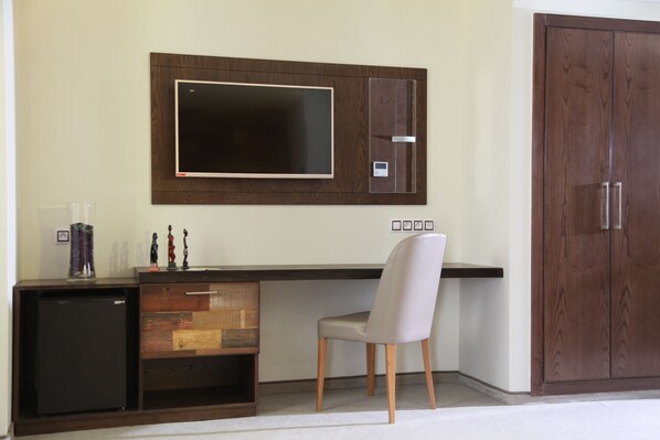 A modern room with a built-in desk, a flat-screen TV, a wardrobe, and a compact refrigerator. - Business Hotel Sfax (Sfax)