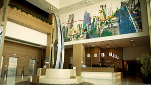 A modern hotel lobby with a reception desk, a seating area, and a large abstract mural on the wall. - DoubleTree by Hilton Ankara Ankamall (Ankara)