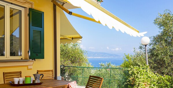 A terrace with a table and chairs, a view of the sea, and a lamp post.