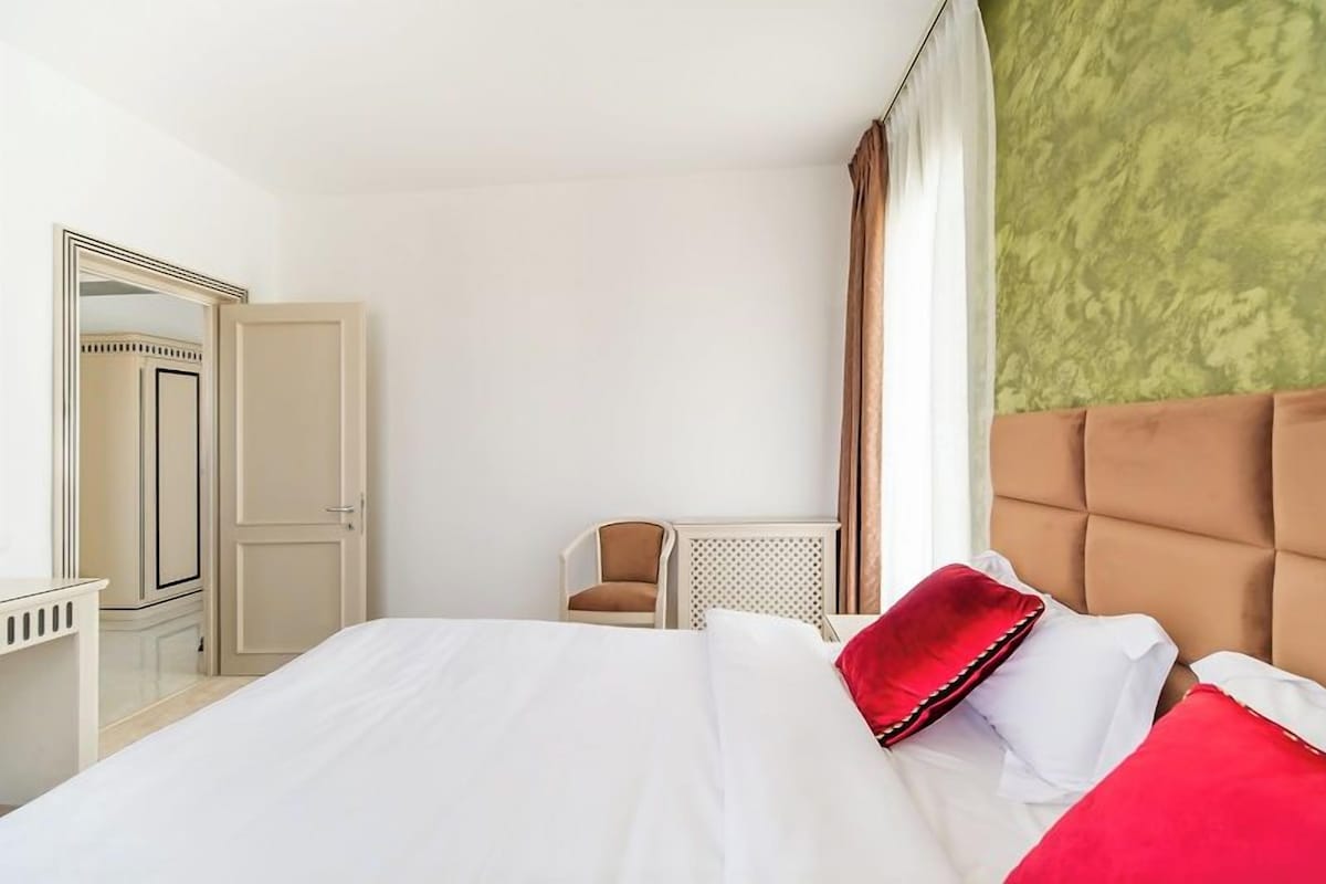 Una habitación de hotel con una cama, una silla, un armario y un espejo.