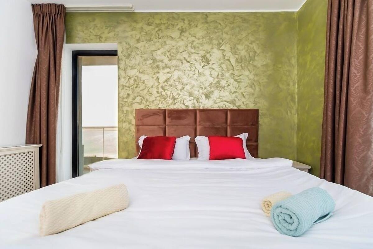 Habitación de hotel con una cama grande, un cabecero y vistas a través de una puerta.
