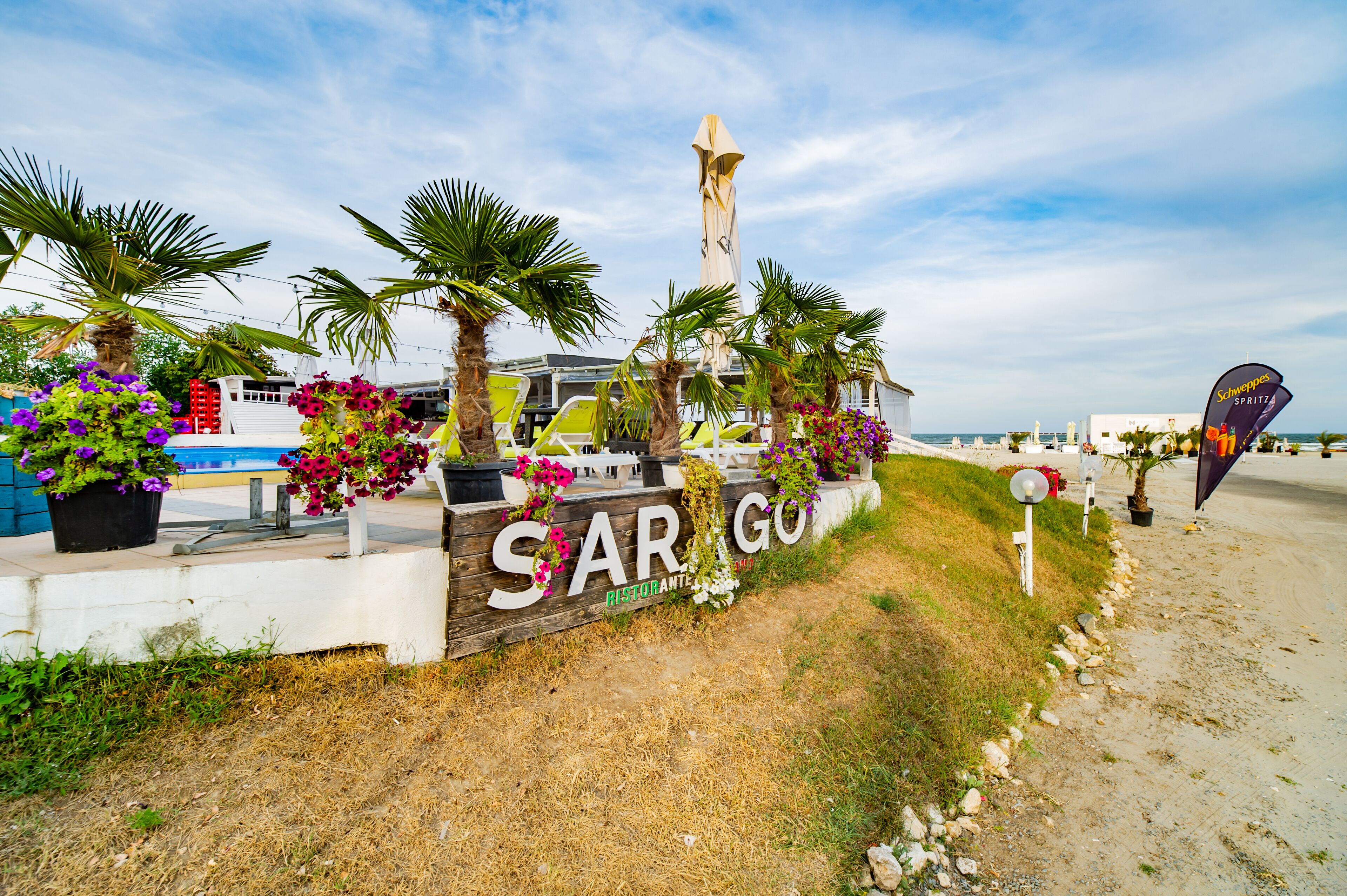 Naamplaatje voor 'SARGON RISTORANTE' met terras en palmbomen.
