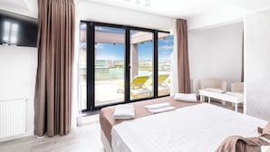 A hotel room with a large bed, a TV, a balcony with a view, and a seating area with chairs. - Miramare Residence (Navodari)