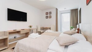 A hotel room with a bed, a desk, a chair, a TV, and a window with curtains.