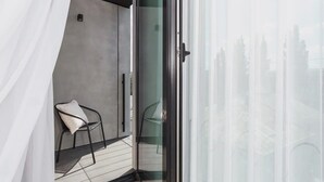 A balcony with a chair and a glass door leading to an outdoor area.