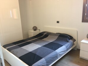 A bedroom with a bed, a bedside table, a lamp, and a wall socket. - Modern house: privacy, air conditioning and unobstructed view of Lake Iseo ★★★★★ (Italia)