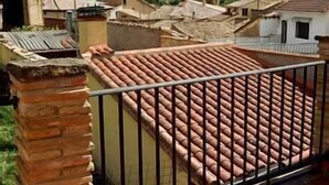 A rooftop terrace with terracotta tiles, a stone pillar, and a metal railing. - Rural house for 4 people (Ayerbe)