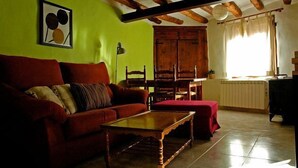 A living room with a red sofa, wooden coffee table, and a wooden cabinet. - Rural house for 4 people (Ayerbe)