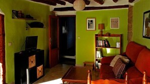 A cozy living room with a red sofa, a wooden coffee table, and a bookshelf. - Rural house for 4 people (Ayerbe)