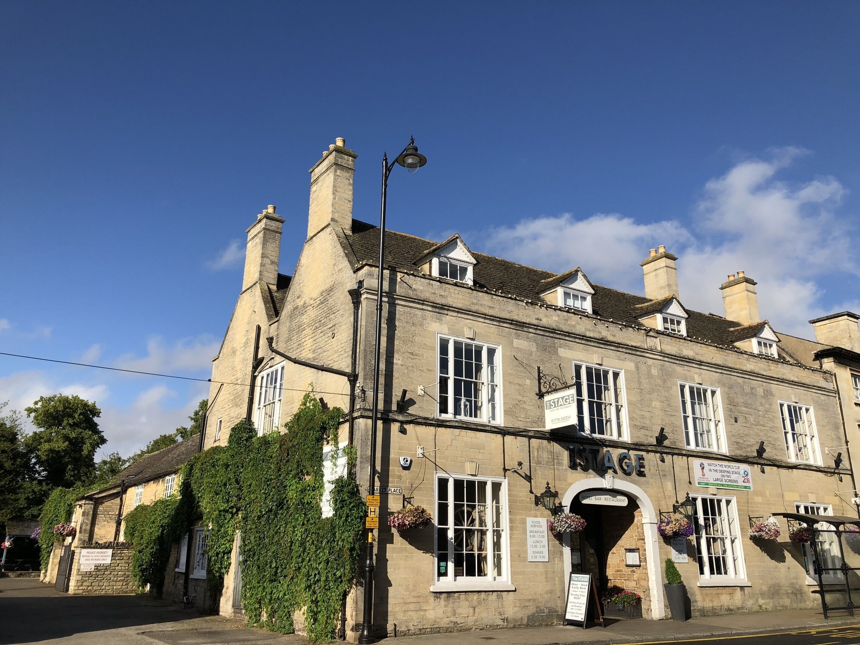 A traditional stone building with a sign reading "The Stage" and a sign for "The Bell Bar Restaurant" below it.