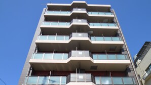Un hotel de varios pisos con un diseño moderno, que cuenta con balcones en cada planta y una entrada destacada con un letrero.