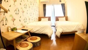 Habitación de hotel con dos camas, un escritorio de madera y una ventana con cortinas.