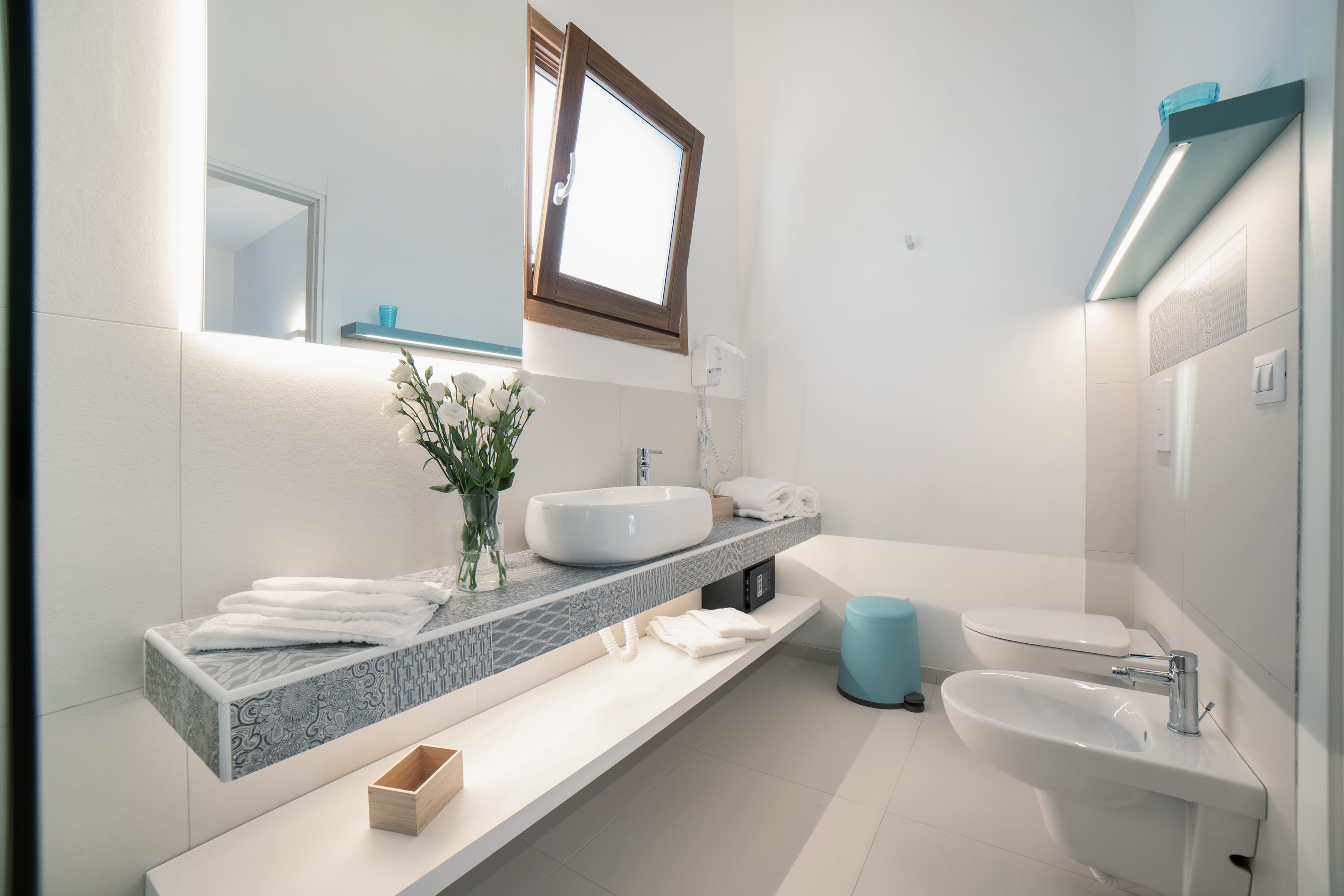 Une salle de bain moderne avec un grand lavabo, un bidet et un miroir au-dessus du meuble-lavabo.
