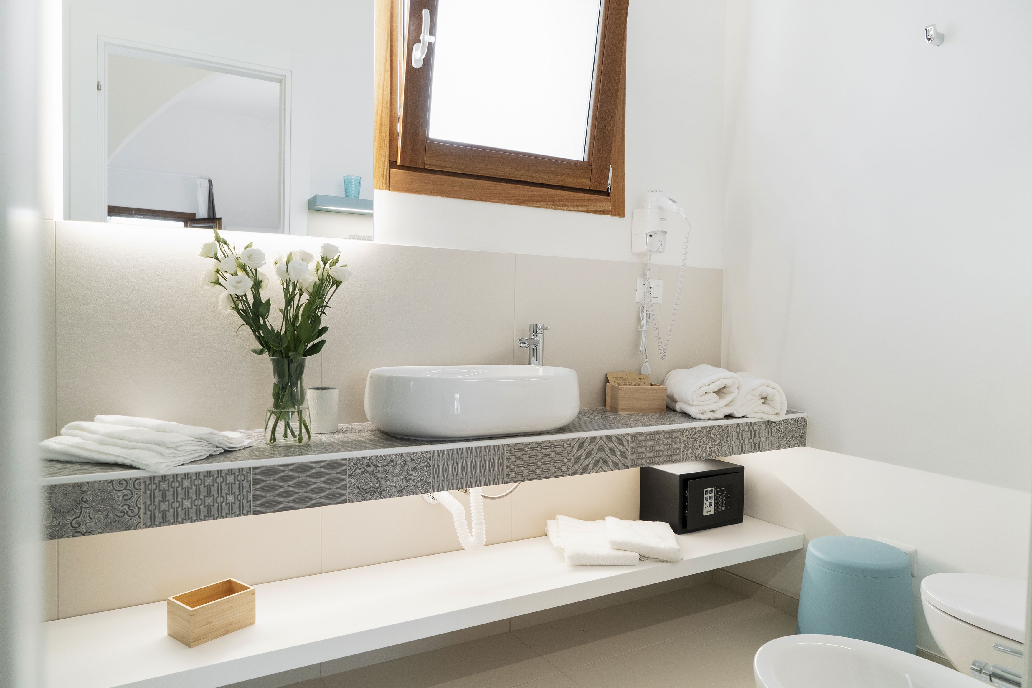 Une salle de bain moderne avec un grand lavabo, un miroir, une fenêtre et des toilettes.