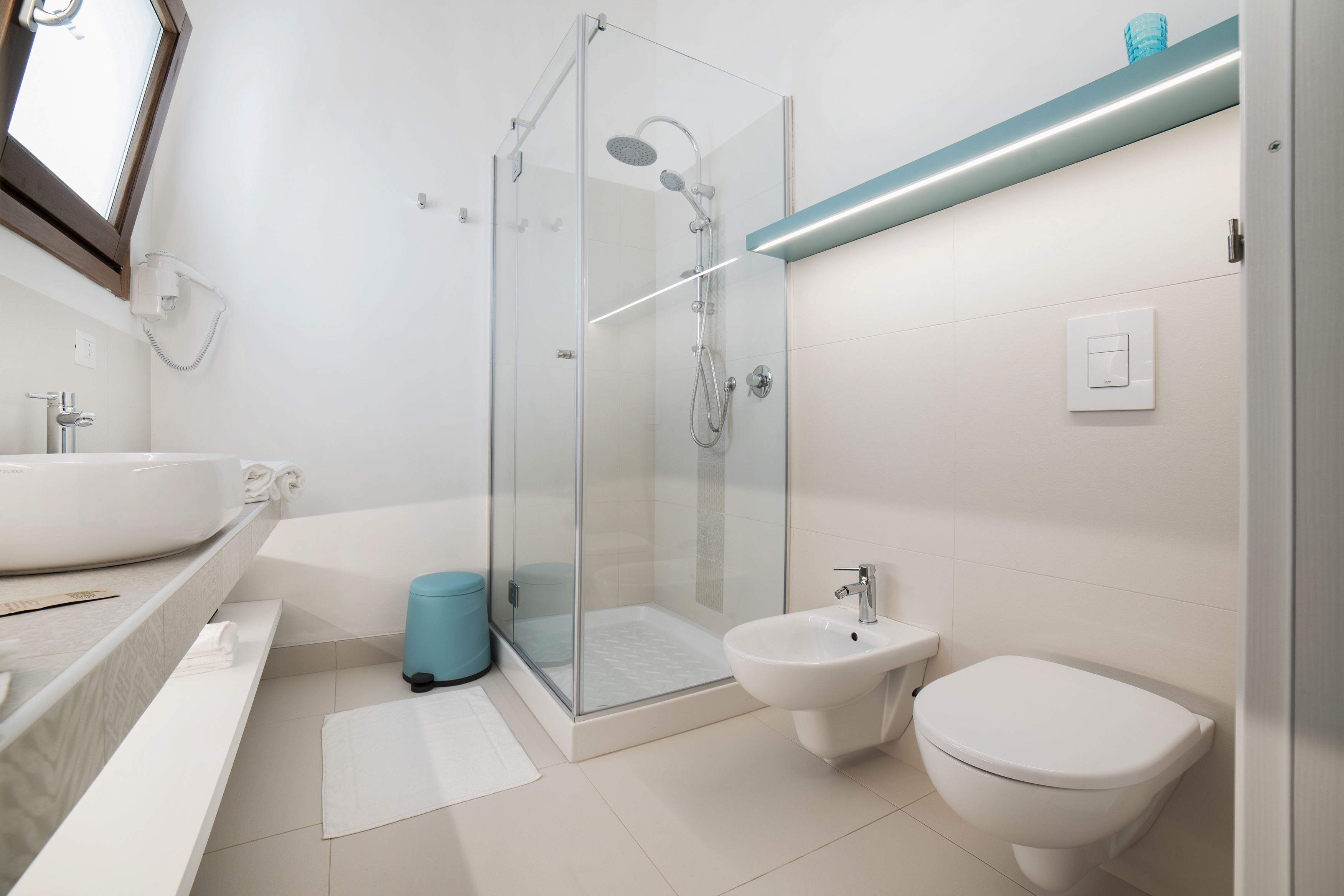 A modern bathroom with a glass-enclosed shower, a bidet, a toilet, and a large sink.