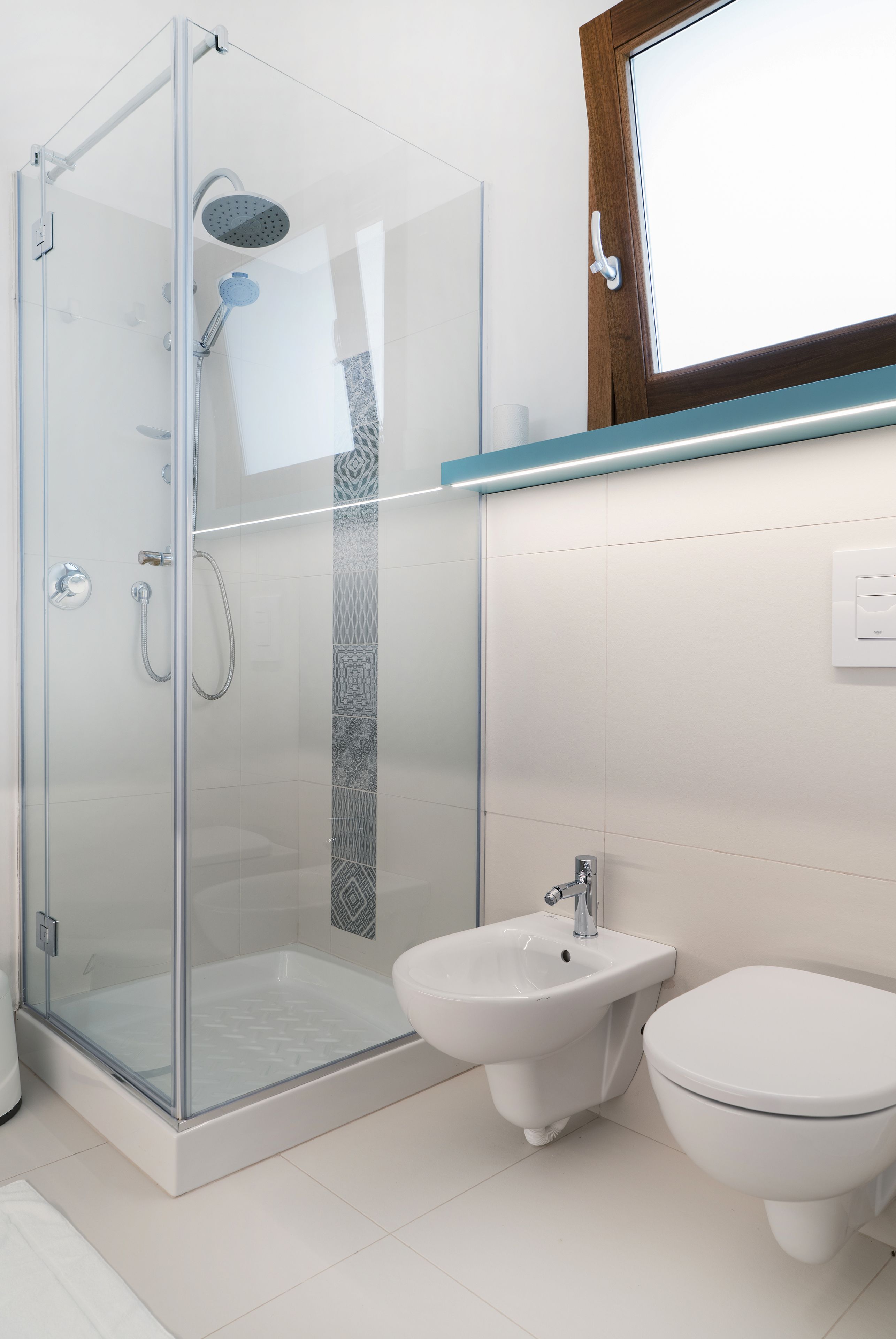 A modern bathroom with a glass-enclosed shower, a pedestal sink, and a toilet.