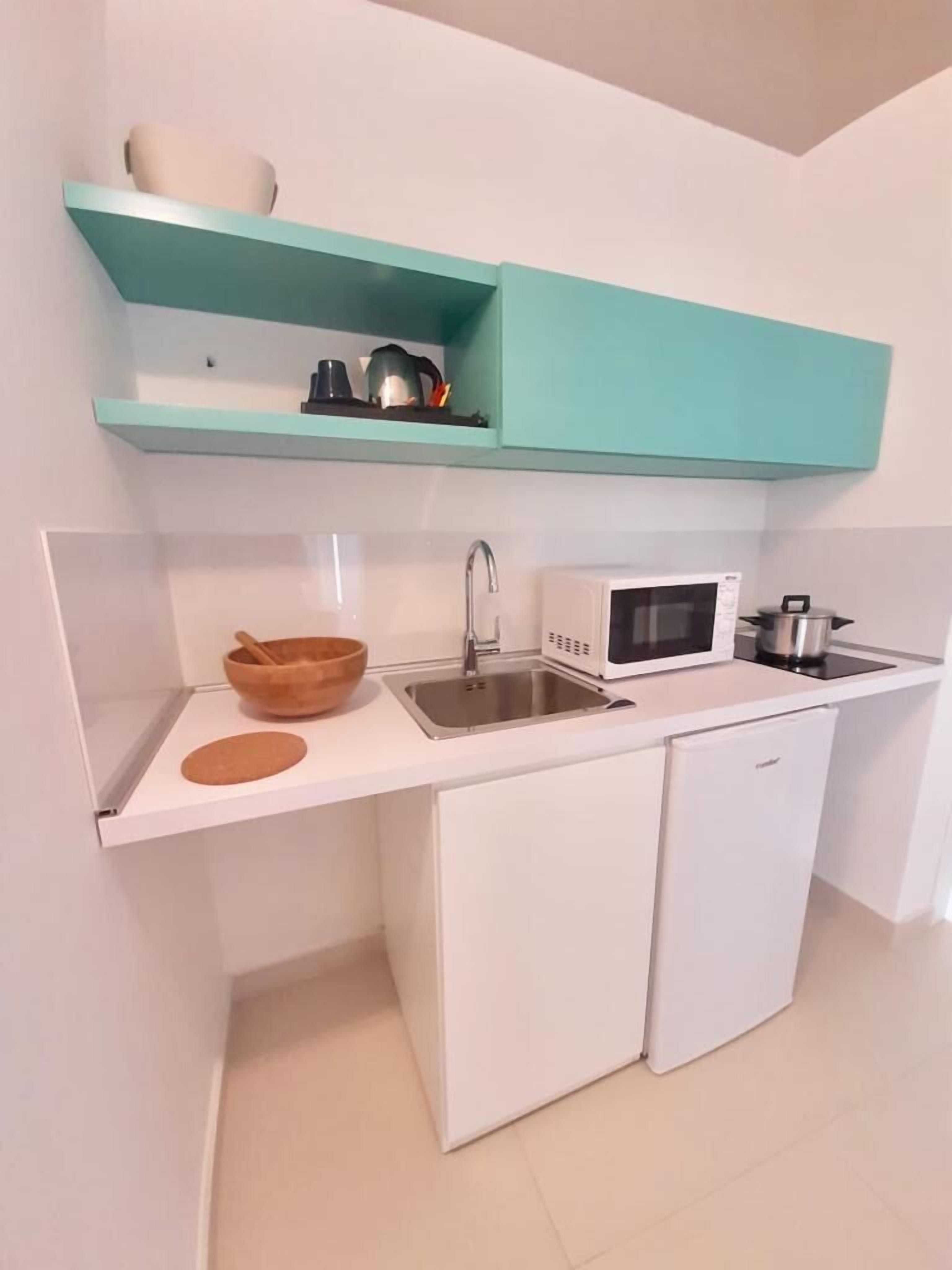A compact kitchen with a sink, microwave, and a small refrigerator.