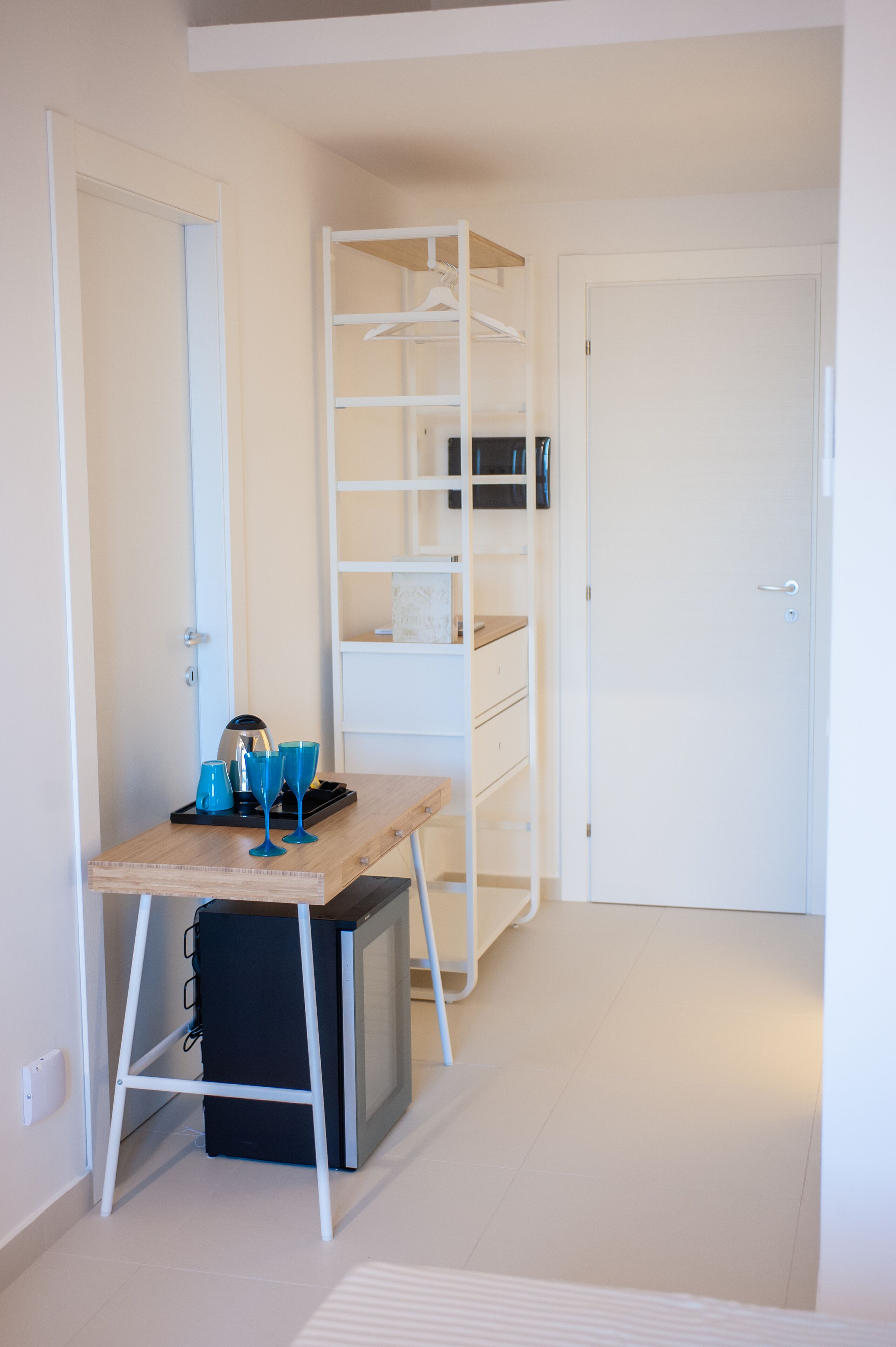 Een compacte, netjes ingerichte kamer met een bureau, planken en een kledingkast.