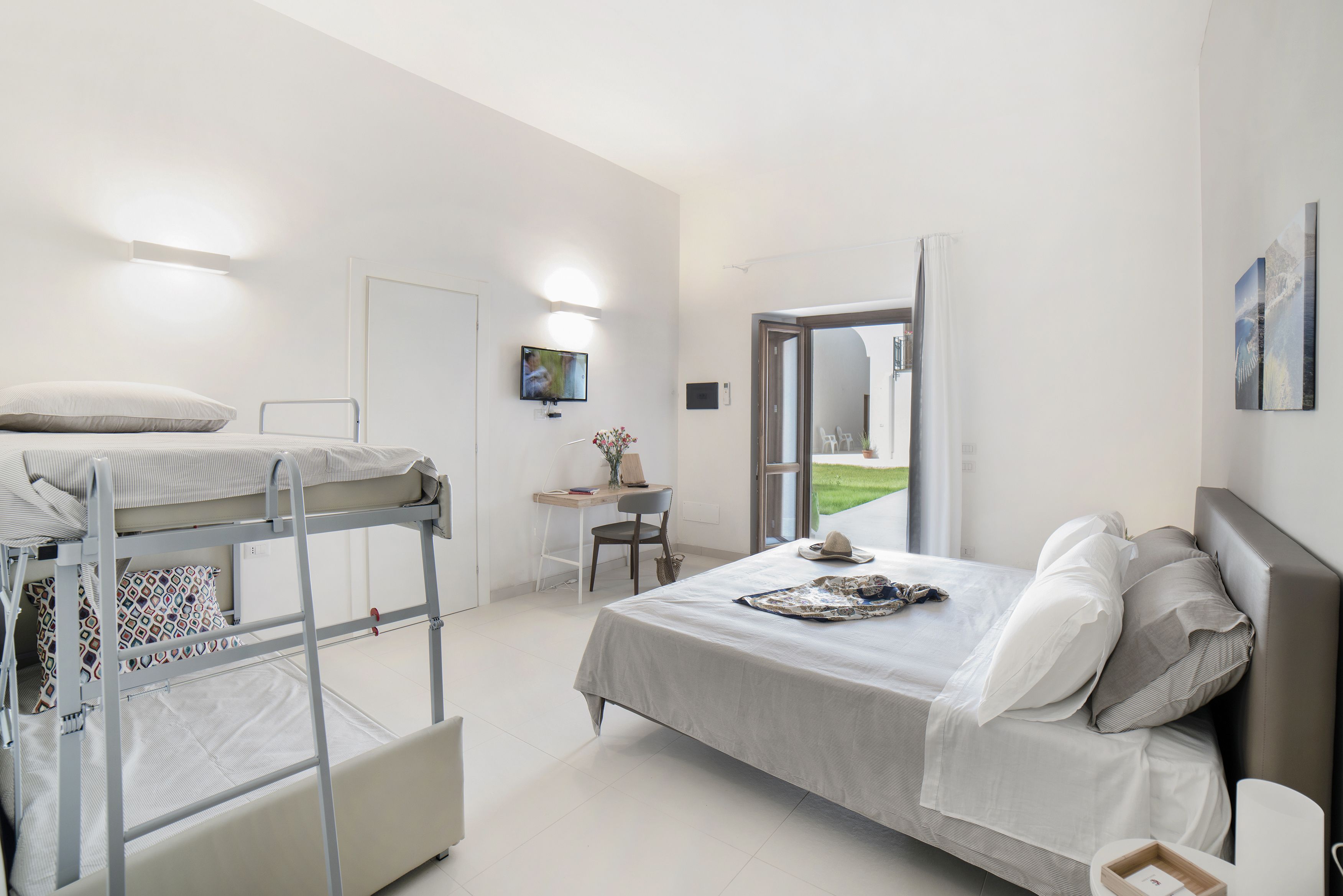 Quarto moderno com beliches, escrivaninha e uma janela grande.