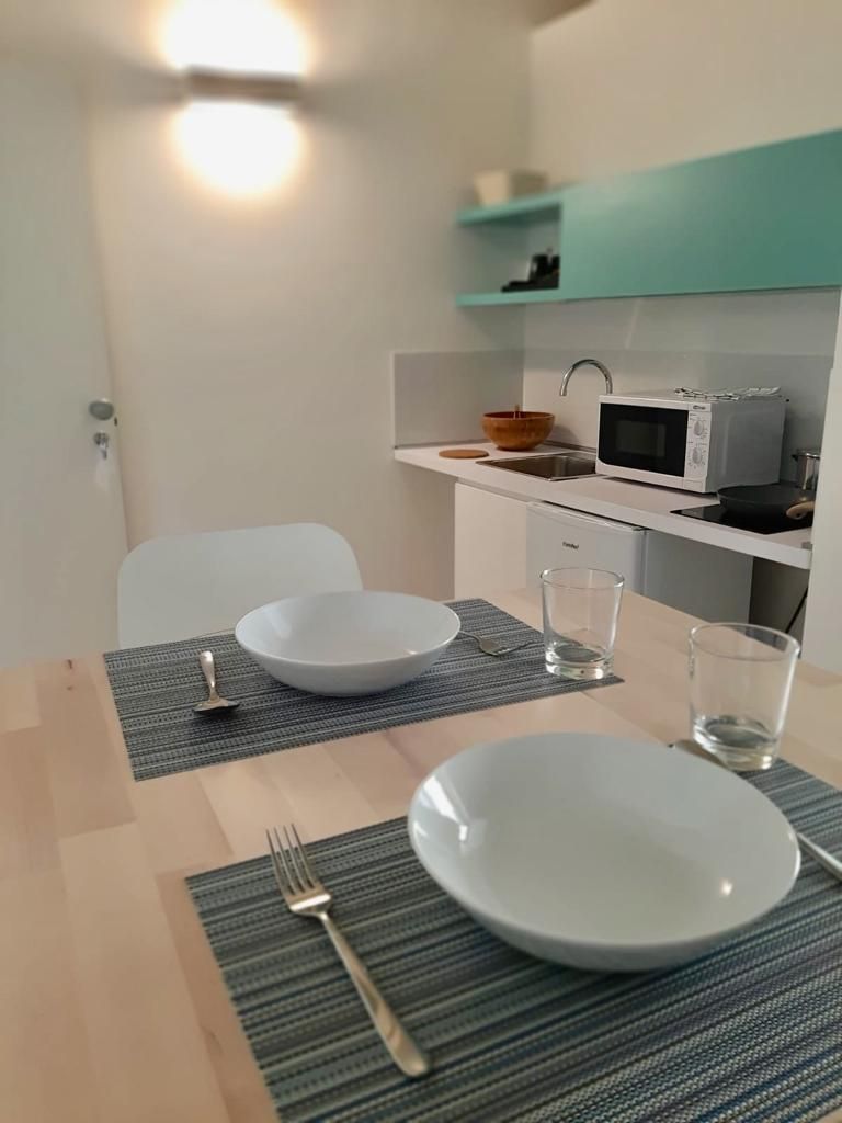 Una mesa de comedor con dos platos blancos, un tenedor y dos vasos, sobre un camino de mesa a rayas.