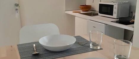 Una mesa de comedor con dos platos blancos, un tenedor y dos vasos, sobre un camino de mesa a rayas.