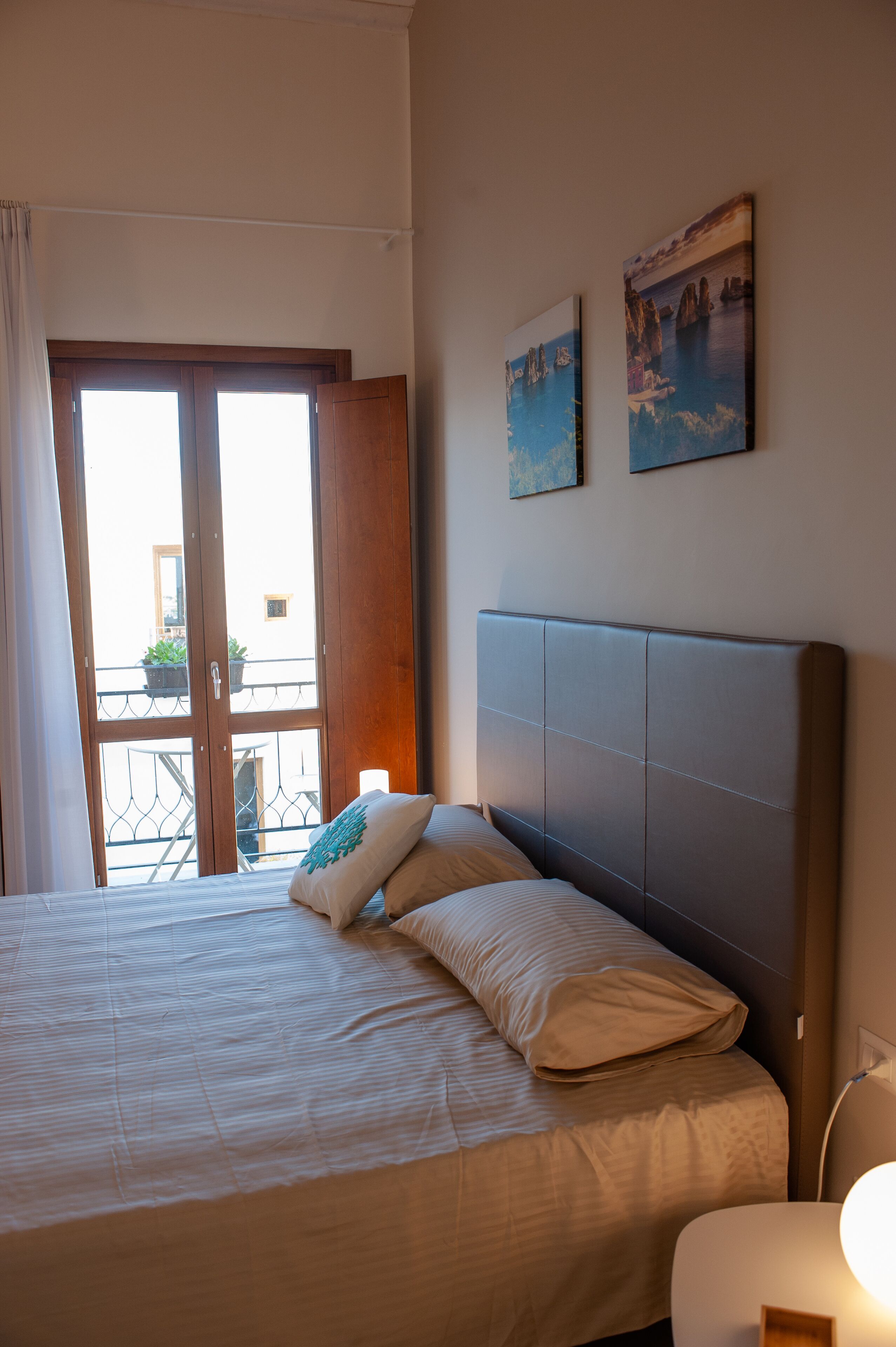 A bedroom with a bed, a nightstand, and a view of the outside balcony.